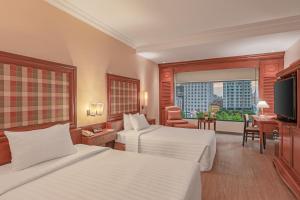 a hotel room with two beds and a television at Hotel Cambodiana in Phnom Penh