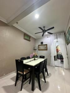 a dining room with a table and chairs and a ceiling fan at Reisya Homestay in Kepala Batas