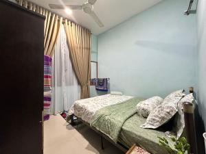 a bedroom with a bed with a green comforter at Reisya Homestay in Kepala Batas