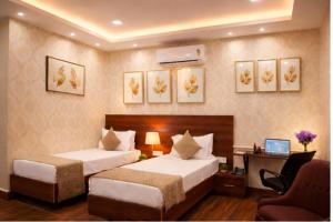 a hotel room with two beds and a desk at Grand Maalyasa Hotel and Suites, US Consulate Hyderabad 2 Mins walk in Hyderabad +26 photos
