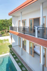 a house with a balcony and a swimming pool at Nang Aji House in Ungasan