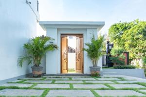 a front door of a white house with two potted plants at Nang Aji House in Ungasan