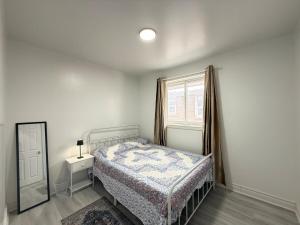 a bedroom with a bed and a window and a mirror at Spacious 2 BR Suite with Parking, Backyard & Desk in Toronto