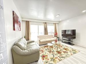 a living room with a couch and a television at Spacious 2 BR Suite with Parking, Backyard & Desk in Toronto