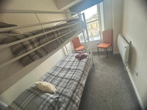 a bedroom with a bunk bed and two chairs at Acorn Apartment in Dufftown