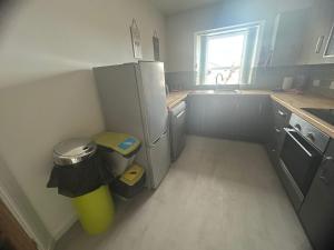 a small kitchen with a refrigerator and a trash can at Acorn Apartment in Dufftown +10 photos