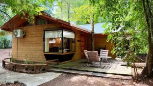 a small cabin in the woods with a table and chairs at Cabaña Roca Volcán in Melipeuco