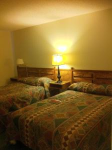 a bedroom with two beds and a lamp on a table at Cataline Motor Inn in Fraser Lake