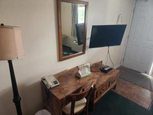 a room with a desk with a television and a mirror at Cataline Motor Inn in Fraser Lake
