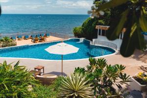 a swimming pool with an umbrella next to the ocean at Pinnacle Koh Tao Resort in Ko Tao +106 photos