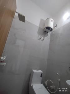 a white bathroom with a toilet and a light on the wall at Naval Kishori Kunj in Vrindāvan