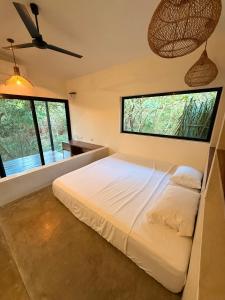 a bedroom with a large bed with two large windows at Calma Ometepe in Santa Cruz