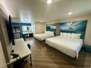 a hotel room with two beds and a desk at Costa Mesa Inn - Newport Beach Area in Costa Mesa