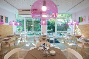 un restaurante con mesas, sillas y luces rosas en fab Hotel en Múnich