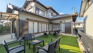 a patio with chairs and tables on a lawn at LandHouse Kani Nagasaka in Kani