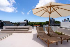 a patio with two chairs and an umbrella on a roof at SandWave Villa by Betterplace in Ungasan