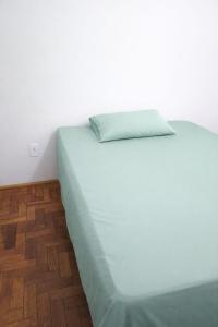 a white bed with a green pillow on top of it at Quarto em Barretos, simples com paz e harmonia in Barretos