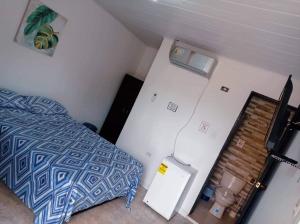 a small bedroom with a bed and a refrigerator at Sweetroom Miss Gloria in Estación El Salto