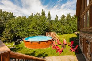 a patio with a hot tub and chairs on a yard at Fiddler Lake Resort - Deer 68 in Mille-Isles