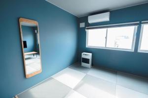 a blue room with a mirror and a window at B Cycleトリプルルーム in Biei