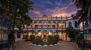 a large white building with a courtyard at dusk at Chettinadu Mansion – An Authentic Heritage Palace in Kānādukāttān
