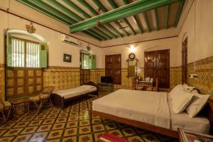 a bedroom with a bed and a couch in a room at Chettinadu Mansion – An Authentic Heritage Palace in Kānādukāttān +36 photos