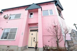 a pink house with a black roof at B Cycleトリプルルーム in Biei