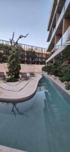 a swimming pool with benches and a building at Amplio Estudio con Balcon Tuk 004 in Tulum