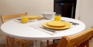 a white table with two plates and two glasses of orange juice at Departamento boutique céntrico in San Miguel de Tucumán +5 photos