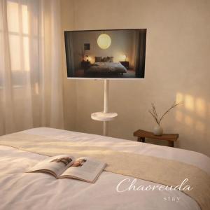 a book on a bed with a tv on the wall at 건대역5분 성수 감성숙소 5 min walk to Konkok Univ Station # 6-Minute Walk to Airport Limousine # Seongsu Cafe Street Walking Tour Hotspots & Pop-up Stores #Seoul Forest # Thukseom Han River Park #KSPO # COEX #Gangnam in Seoul