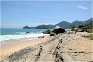 a person walking on a beach near the ocean at Casa na Mata - 2 min da Praia de fora com WiFi in Paraty