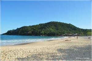 a sandy beach with a island in the ocean at Casa na Mata - 2 min da Praia de fora com WiFi in Paraty +2 photos