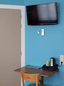een houten tafel met een televisie aan een blauwe muur bij Hoevehotel Ronse in Ronse
