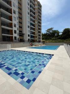 a swimming pool in front of two tall buildings at Comodidad, sol y descanso total in Melgar
