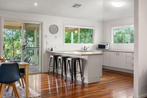 a kitchen with white cabinets and a counter with bar stools at Hinterland Tranquil Escape with Beautiful Views in Ninderry