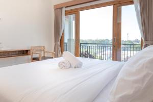 a bedroom with a white bed with a balcony at Nang Aji House in Ungasan
