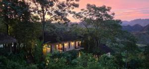 a house in the middle of a forest at sunset at Pu Luong Eco Garden in Pu Luong