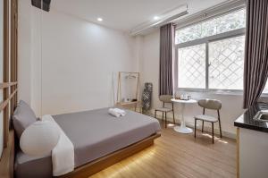 a bedroom with a bed and a table and a window at V Living - Airport Stopover with Free Laundry in Ho Chi Minh City