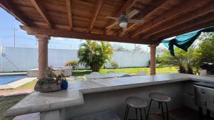 an outdoor bar with stools under a wooden pergola at Home in Tequesquitengo in Tequesquitengo
