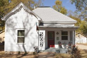 a small white house with a red door and a flag at Poppy's Place in Chanute
