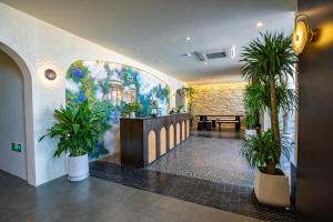 a lobby with potted plants and a painting on the wall at Bay Four Seasons Castle Hotel in Weihai