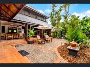 a house with a patio with a table and an umbrella at Solander Beachfront with private beach access & pool in Port Douglas