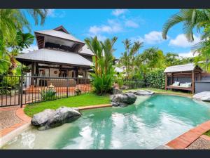 a swimming pool in front of a house at Solander Beachfront with private beach access & pool in Port Douglas