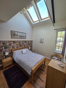 a bedroom with a bed and two windows at Wagtail Cottage in Kilmartin