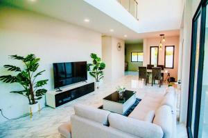 a living room with white furniture and a flat screen tv at The Hide Private in Ban Non Sa-at