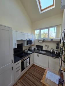 a kitchen with white cabinets and black counter tops at Wagtail Cottage in Kilmartin +12 photos