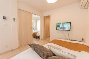 ein Schlafzimmer mit einem Bett und einem Fernseher an der Wand in der Unterkunft Mi-Hotel Ikebukuro 池袋 in Tokio