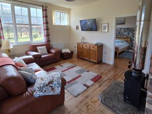 a living room with a leather couch and a table at Wagtail Cottage in Kilmartin