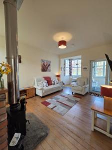 a living room with two white couches and a fireplace at Siskin Cottage in Lochgilphead