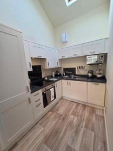 a kitchen with white cabinets and a wooden floor at Siskin Cottage in Lochgilphead +12 photos